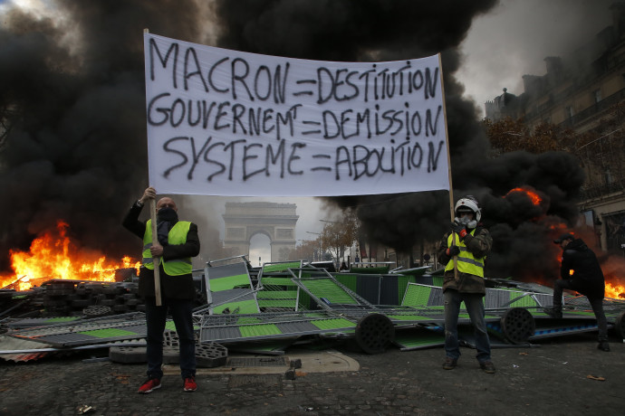 Macron-ellenes transzparenst tartanak sárga mellényes tüntetők a Champs-Elysées sugárúton Párizsban 2018. november 24-én. Országszerte csaknem 81 ezren vonultak utcákra békés tüntetéseken, a fõvárosban 8 ezren tiltakoztak az erõszakossá fajult megmozduláson. Fotó: MTI/AP/Michel Euler