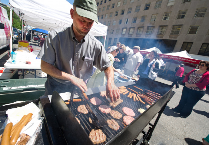 Kinley Coulter owner of Colter Farms grills homemade sausages and beef patties on May 2, 2013 at the farmer's market near the White House in Washington, DC. The Colter family produces certified organic 100 percent grass fed beef, lamb and free range eggs on their 220-acre (89-hectare) farm located in Honey Grove, Pennsylvania. AFP PHOTO / Karen BLEIER (Photo by KAREN BLEIER / AFP)