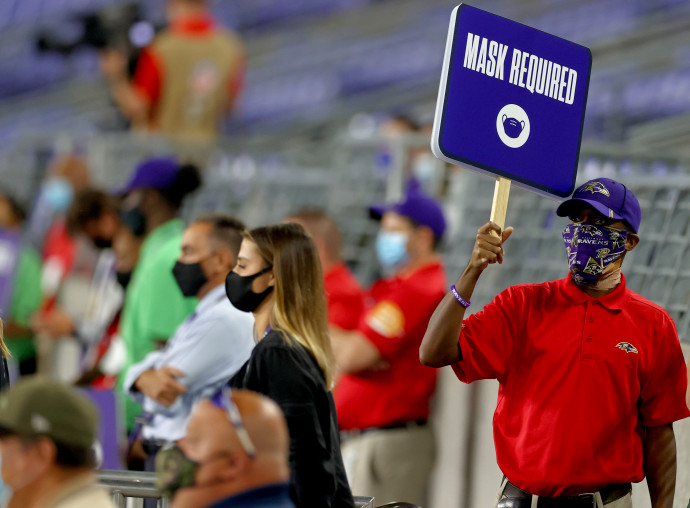 „Maszk viselése kötelező” feliratú táblát tart egy férfi egy NFL meccsen 2020 szeptember 28-án.Fotó: Todd Olszewski / AFP