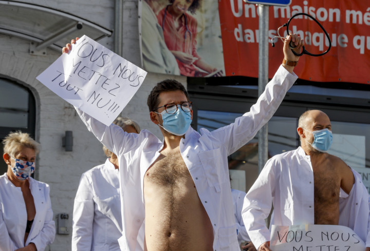 Orvosok és egészségügyi dolgozók nagyobb állami támogatást követelve tüntettek egy kórház előtt Charleroi-ban október 26-án. A felirat jelentése: mindannyiunkat meztelenre vetkőztettek. Fotó: Olivier Hoslet / MTI/EPA