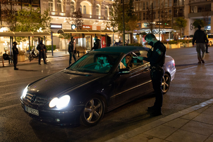 Rendőr ellenőriz egy autóst október 25-én éjszaka a korábbi éjszakai kijárási korlátozás idején. – Fotó: Alkis Konstantinidis / Reuters