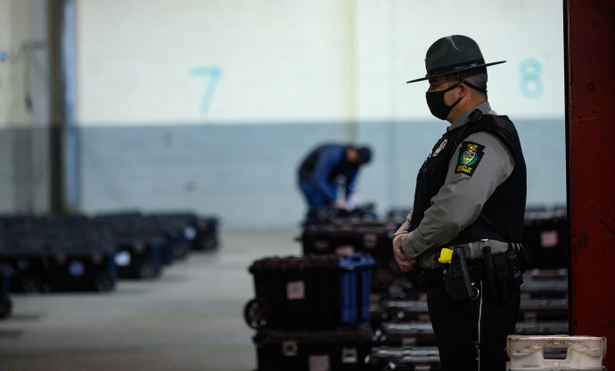 Allegheny megyei szavazólapokat, választási anyagokat és a szavazógépek kulcsait tartalmazó bőröndöket őriz egy rendőr Pittsbourghben, Pennsylvania államban 2020. november 4-én – Fotó: Jeff Swensen / Getty Images / AFP