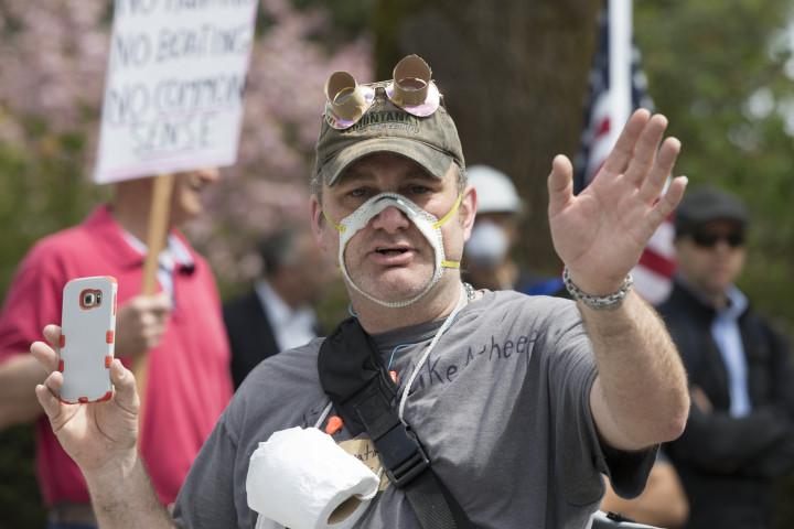Egy férfi kivágott maszkkal tiltakozik a kijárási korlátozások ellen a washingtoni Capitolium épülete előtt 2020. április 19-én – Fotó: Karen Ducey / Getty Images
