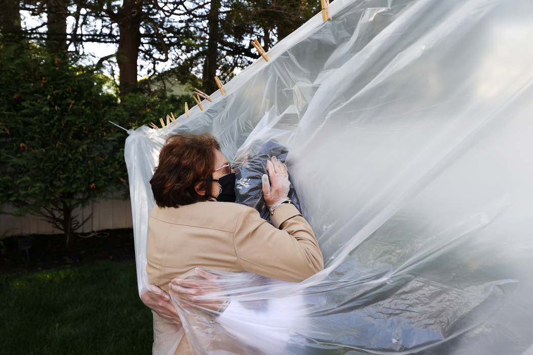 Egy New York-i nő csak maszkban, kesztyűben, egy műanyag fólián keresztül ölelte meg az édesanyját a járvány alatt 2020. május 24-én – Fotó: Al Bello/Getty Images