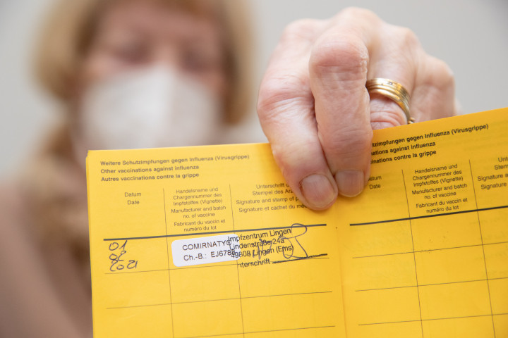 Egy német nyugdíjas mutatja az oltási könyvébe ragasztott matricát, ami igazolja, hogy megkapta a Pfizer-BioNTech első koronavírus elleni oltását 2021. február 1-jén – Fotó: Friso Gentsch / DPA / AFP