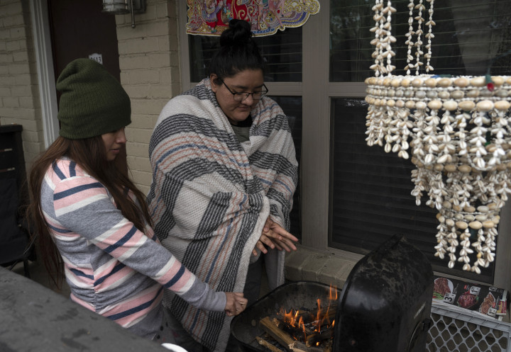 Az áramkimaradás miatt egy grill mellett állva melegszenek Houstonban 2021. február 16-án – Fotó: Go Nakamura / Getty Images / AFP
