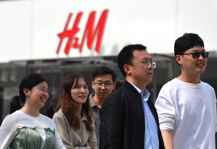 Egy pekingi H&M előtt elsétáló emberek 2021. március 25-én – Fotó: GREG BAKER / AFP