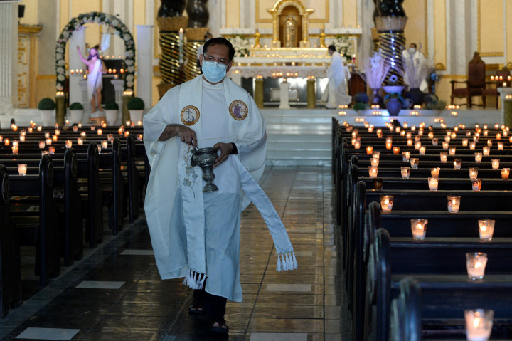 Egy katolikus pap meggyújtott gyertyák mellett halad el egy üres templomban a Fülöp-szigeteken. A kormány szigorított járvány elleni intézkedésein, miután a fővárosban és az ahhoz közeli tartományokban a fertőzések száma megugrott. – Fotó: Lisa Marie David / Reuters
