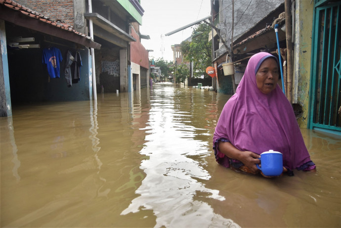 Indonéz nő Jakarta egyik elárasztott negyedében idén februárban. Fotó: AFP