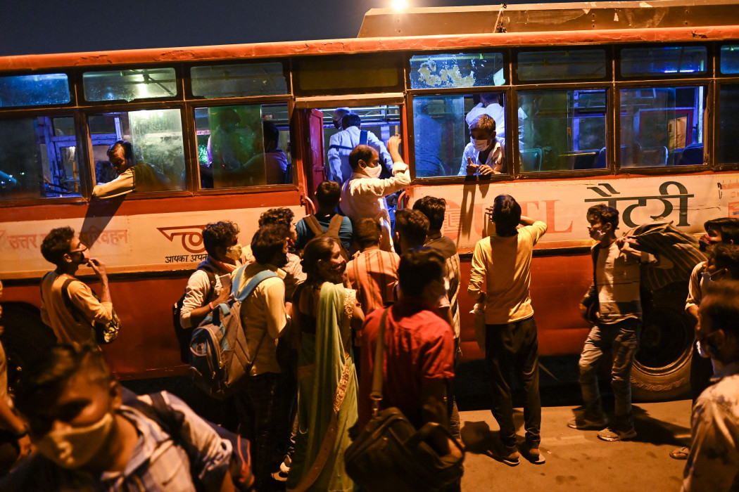 Ingázók szállnak fel egy buszra Újdelhiben 2021. április 19-én – Fotó: Sajjad Hussain / AFP