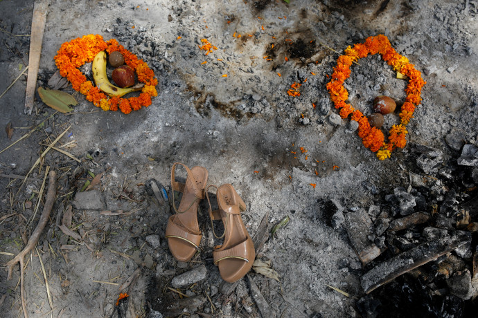 Családtagok virágfüzéreket, gyümölcsöket és egy szandált tettek egy koronavírusban meghalt nő hamvasztásának helyére – Fotó: Adnan Abidi / Reuters
