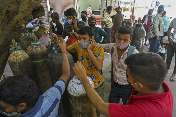 Oxigénpalackjuk újratöltésére várakozók Újdelhiben. Az oxigént az otthon ápolt koronavírusosoknak viszik – Fotó: Prakash Singh / AFP