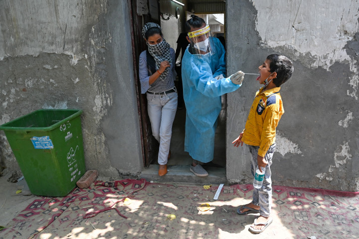 PCR-teszthez vesz mintát egy kisfiútól egy egészségügyi dolgozó Gáziábádban – Fotó: Prakash Singh / AFP