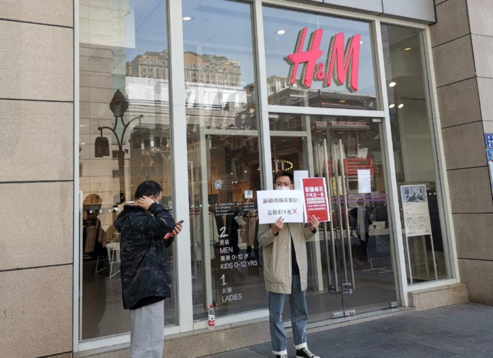 Egy férfi egy kínai H&M előtt az üzlet bojkottjára felhívó táblával 2021 márciusában – Fotó: EyePress News / AFP