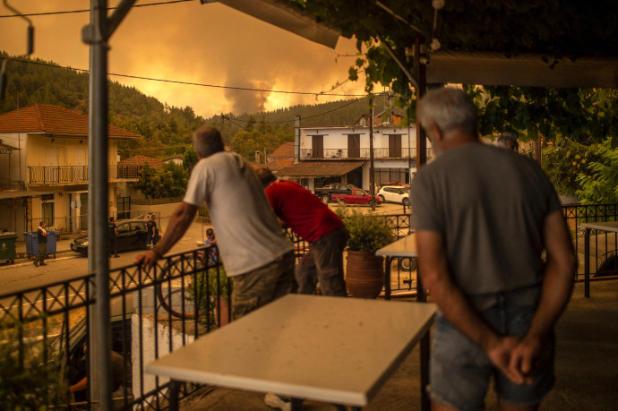 Lakók nézik a közeledő tüzet egy településen Évia szigetén 2021. augusztus 8-án – Fotó: Angelos Tzortzinis / AFP