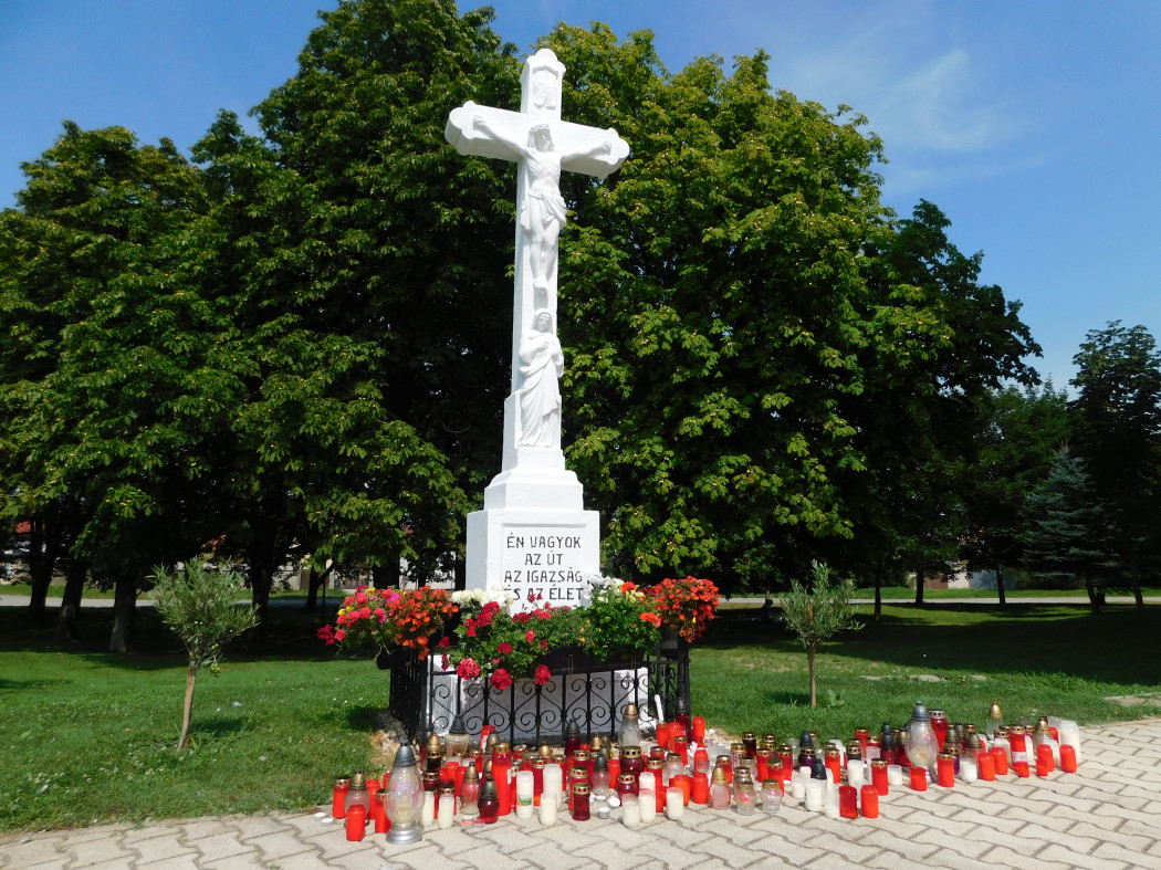 Több tucat mécses fekszik a bezenyei templom melletti keresztnél. Az elhunyt helyi áldozatokra emlékeztek a falubeliek – Fotó: Cséfalvay Attila / Telex