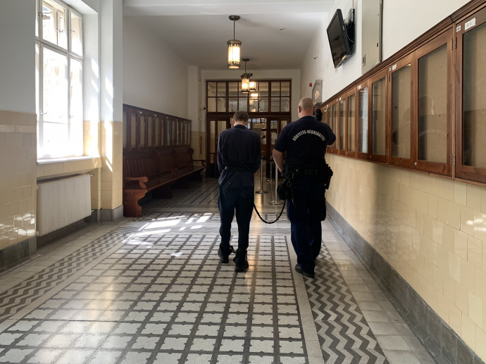 A vádlott férfit bilincsben vezetik a Pesti Központi Kerületi Bíróság folyosóján 2021. augusztus 25-én – Fotó: Pintér Luca / Telex