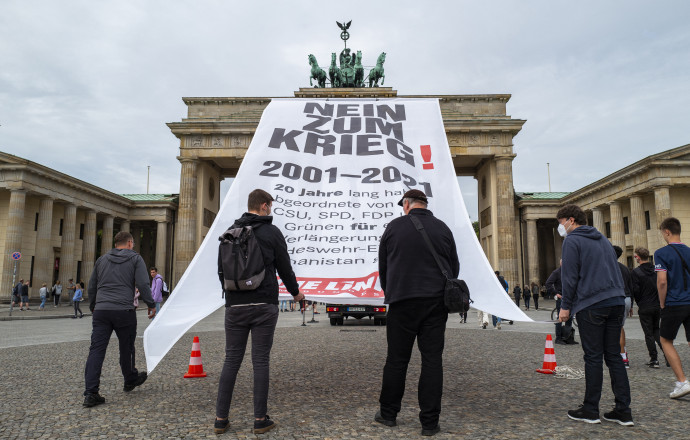 „Nemet a háborúra!” kezdetű transzparenst helyeznek ki 2021. augusztus 25-én a berlini Brandenburgi kapura a baloldali Die Linke párt képviselői által rendezett tüntetésen – Fotó: John Macdougall / AFP