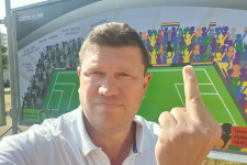 Feltartott középső ujjal fotózta magát az ARC kiállítás szivárványos plakátja előtt az újbudai fideszes képviselő