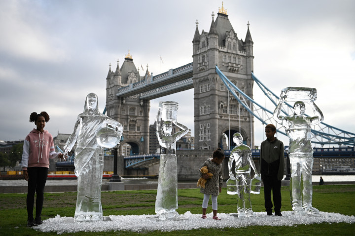 Gyerekek vizet gyűjtő embereket ábrázoló jégszobrokkal Londonban 2021. szeptember 15-én. A Water Aid szervezet a víz fontosságára és a klímaváltozás hatásaira akarja felhívni a figyelmet a performansszal – Fotó: Daniel Leal-Olivas / AFP