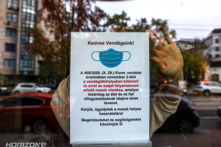 Kötelező maszkviselésre figyelmeztető táblát tesznek ki egy budapesti kávézóban 2020. október 2-án – Fotó: Huszti István / Telex