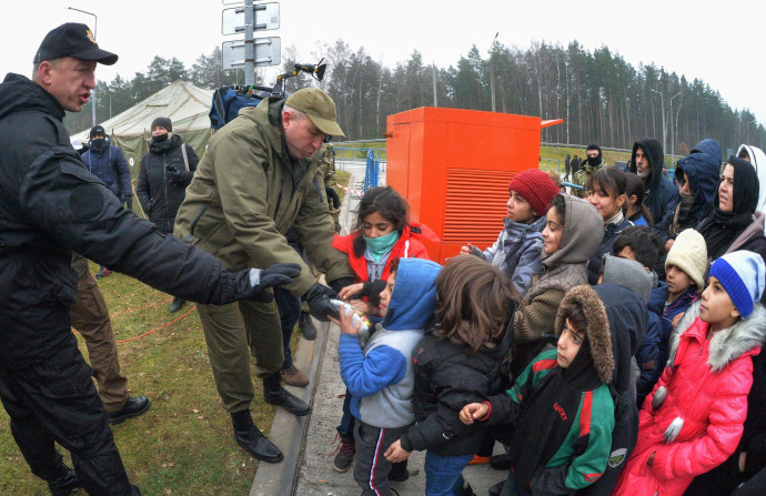 Belarusz katona édességet oszt a menekült gyerekeknek a Bruzgi-Kuznica Bialostocka határátkelőnél – Fotó: Viktor Tolocsko / Sputnik via AFP