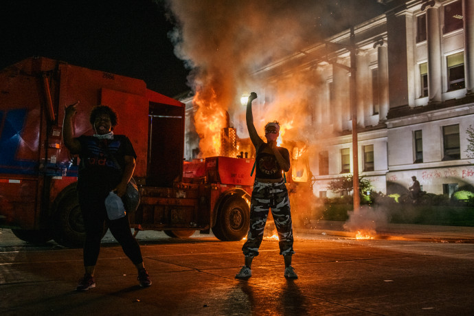 Tüntető pózol egy felgyújtott kukásautó előtt a zavargások második estéjén – Fotó: Brandon Bell / Getty Images North America / Getty Images via AFP