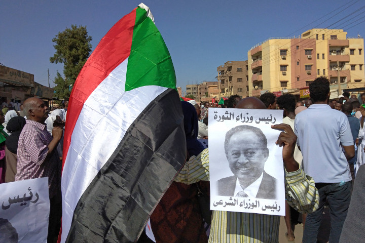 Tüntetők Kartúm utcáin Szudán zászlajával és a megpuccsolt miniszterelnök portréjával november 17-én – Fotó: AFP