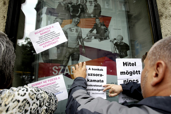 Devizahiteles demonstrálók feliratokat ragasztanak fel egy bankfiók ablakára 2013. augusztus 27-én a fővárosi Nagykörúton – Fotó: Szigetvári Zsolt / MTI