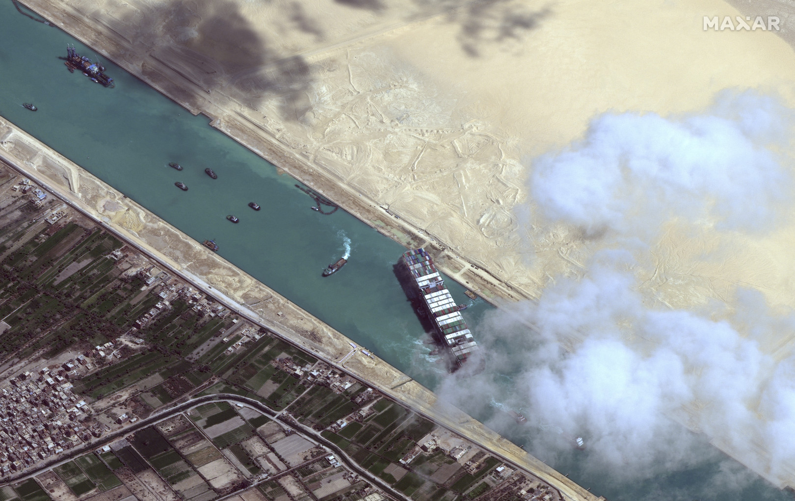 Műholdképen a Szuezi-csatornában keresztbe forduló Ever Given konténerhajó és a kiszabadításán dolgozó vontatóhajók 2021. március 29-én – Fotó: Satellite image – Maxar Technologies / AFP