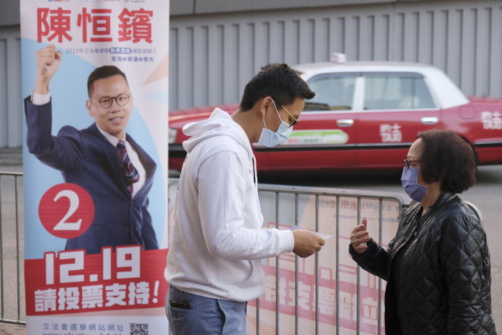 A plakáton látható jelölt, Chan Han-pan beszélget egy választóval december 8-án – Fotó: Wang Shen / Xinhua via AFP