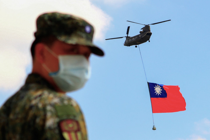 Tajvani katonák állnak őrt, miközben egy tajvani zászlót hordozó helikopter repül a tajvani nemzeti ünnep alkalmából rendezett légi műsor részeként 2021. szeptember 28-án – Fotó: Ceng Shou Yi / NurPhoto / AFP