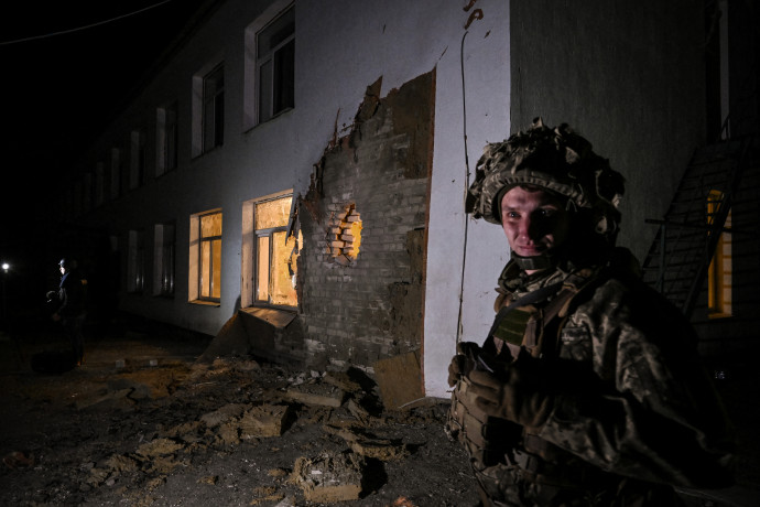 Ukrán katona áll őrt az óvoda mellett, amit találat ért a kelet-ukrajnai szakadár területek közelében – Fotó: Aris Messinis / AFP
