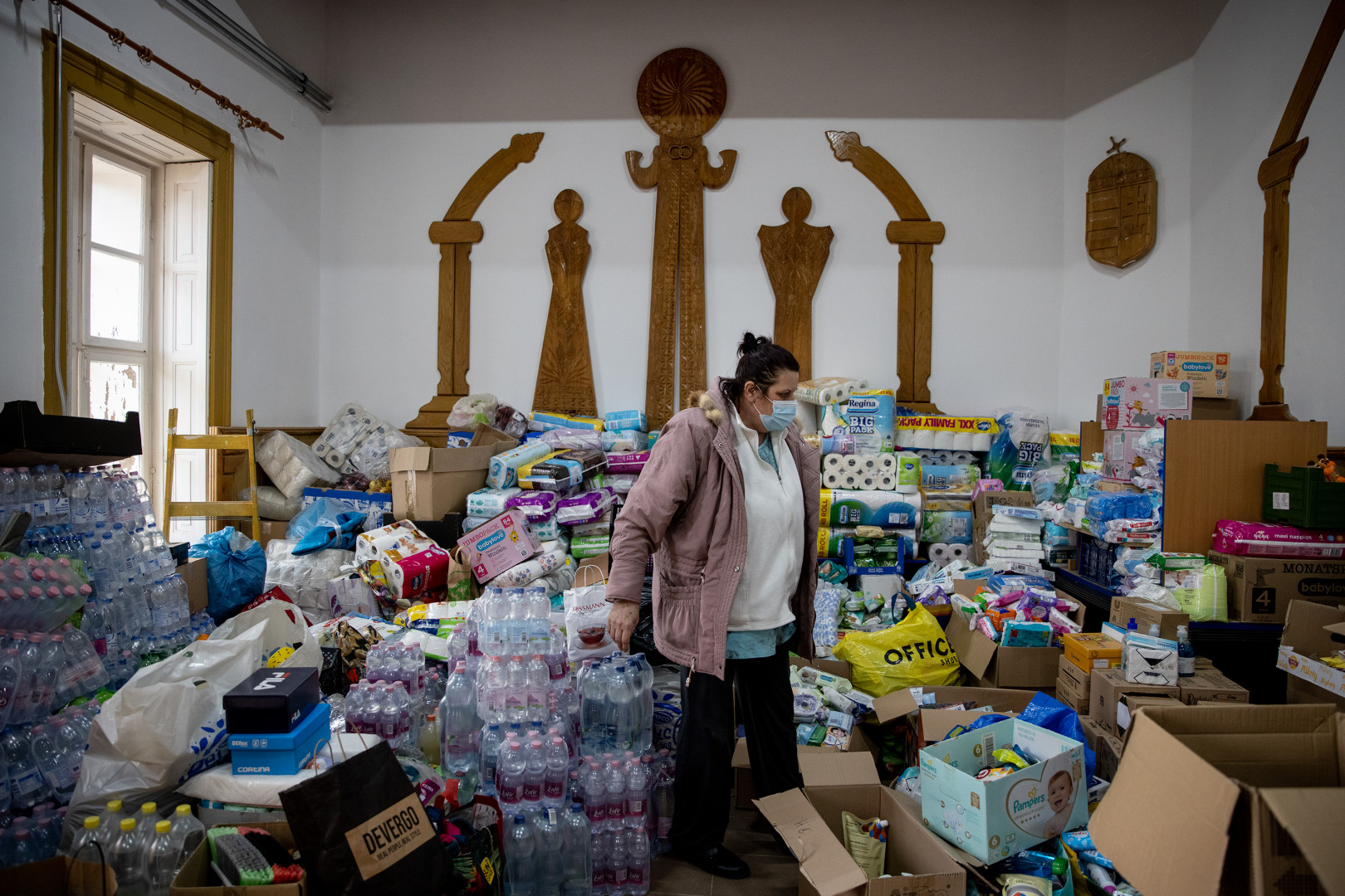 A beregsurányi önkormányzat egyik munkatársa rakodja a beérkező adományokat a művelődési ház egyik szobájában