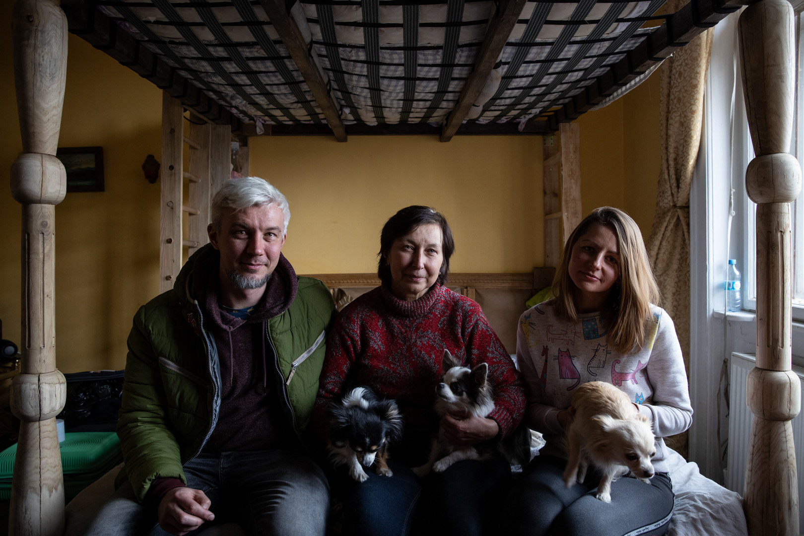 Denis, Olena and Lina in their shared room. The man left Kyiv with his mother, his wife, three dogs and two parrots on the first day of the war. 