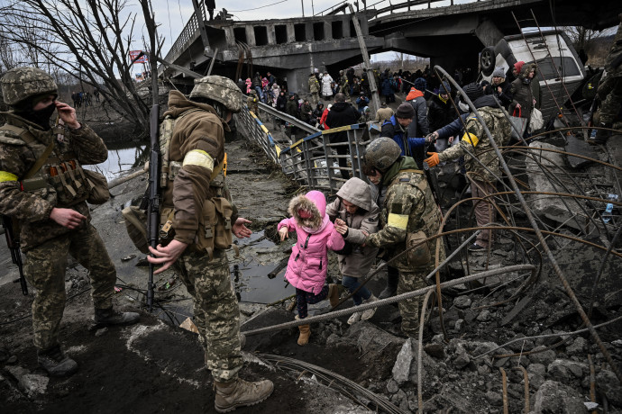 Civileket menekítenek ki az ukrán hadsereg katonái Kijev szétbombázott elővárosából, Irpinyből egy elpusztított hídon keresztül 2022. március 5-én – Fotó: Aris Messinis / AFP