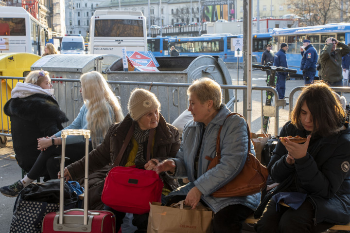 Menekült emberek várnak a Nyugati pályaudvar melletti parkolóban 2022. március 7-én, a háttérben a melegedőbuszok és a transzferbuszok – Fotó: Melegh Noémi Napsugár / Telex