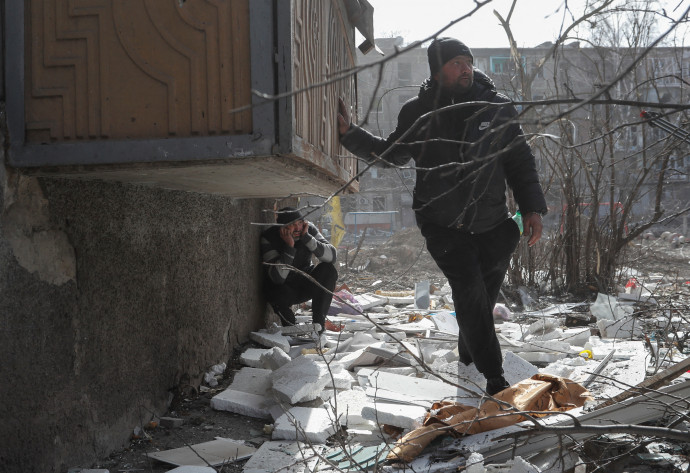 Helyi lakosok Mariupolban közeli robbanásokat hallva fedezékbe húzódnak március 20-án – Fotó: Alexander Ermochenko / Reuters