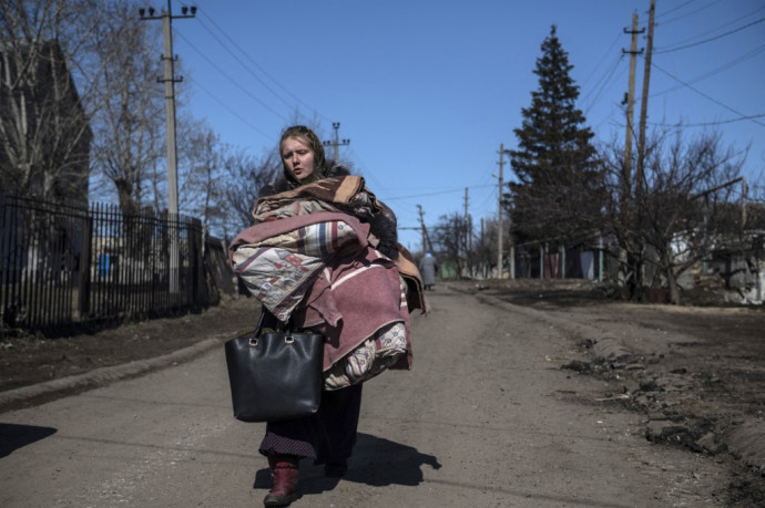 Menekülő nő a luhanszki Varvarovkában egy hétfőn közölt felvételen – Fotó: Valerij Melnikov / AFP