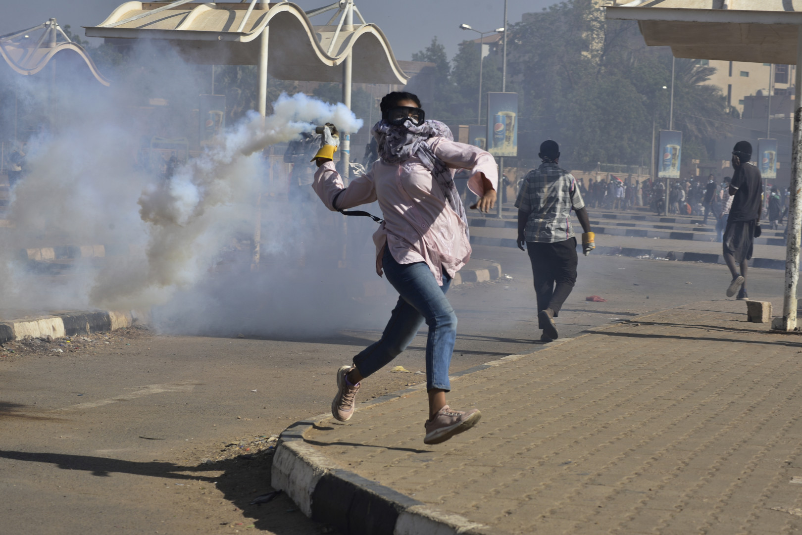 Egy tüntető dobja vissza a könnygázgránátot, amit a biztonsági erők lőttek ki a katonai uralom elleni tüntetésen Kartúmban, Szudán fővárosában 2021. december 30-án.