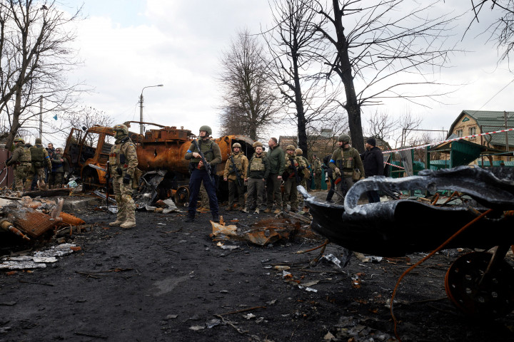 Ukrán katonák megsemmisített orosz harci járművek mellett Bucsában – Fotó: Ukrainian Presidential Press Service / Handout via Reuters
