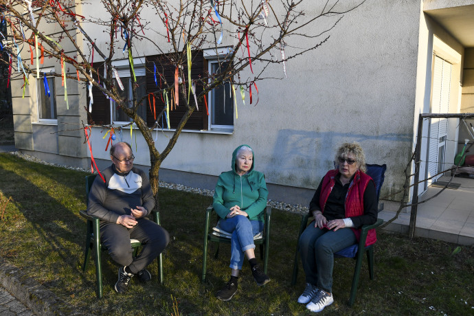 A barackfát a különböző országokból származó szomszédok kezdték feldíszíteni a Covid kezdetén. Alatta a belarusz házaspár és egyik szomszédjuk, a kárpátaljai Zita ül. A másik képen Ljubov kis könyve Hévízről Fotó: Melegh Noémi Napsugár / Telex