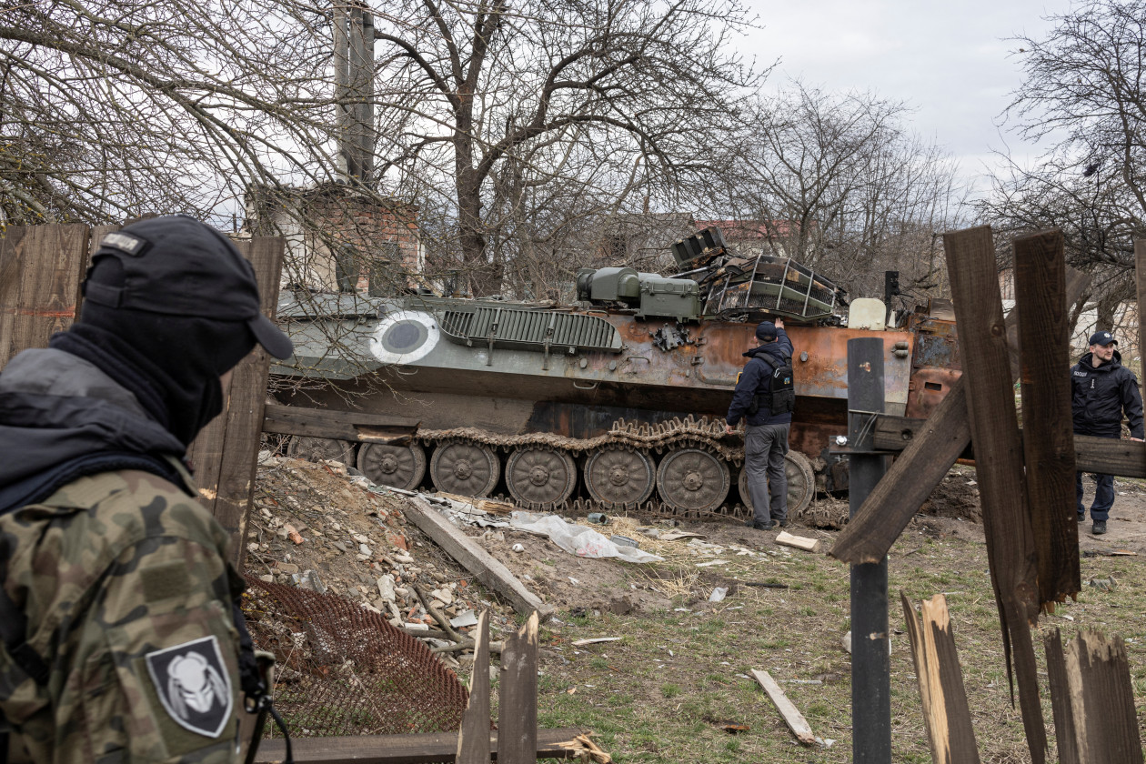 Ukrán katonák vizsgálnak egy sérült orosz harcjárművet / A tűzszerészeti egységek egy tagja kutyával a kezében – Fotó: Marko Djurica / Reuters