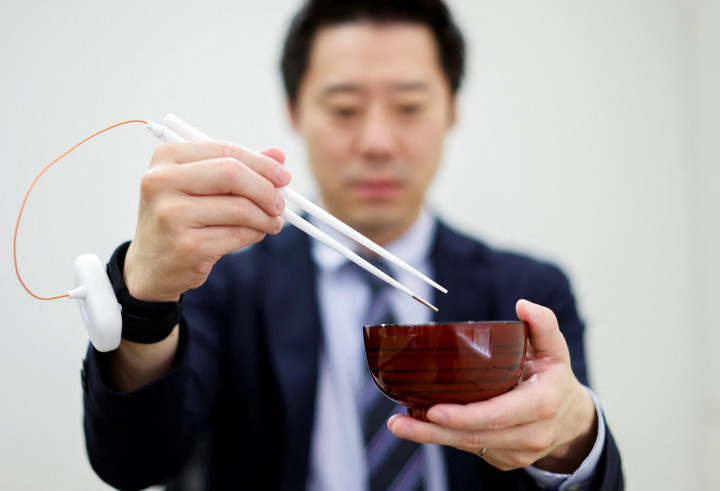 A Kirin Holdings munkatársa bemutatja az ízfokozó evőpálcikát – Fotó: Issei Kato / Reuters