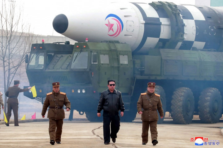A Koreai Központi Hírügynökség által 2022. március 25-én kiadott fotó Kim Dzsongunról, és mögötte az állítólagos Hvaszong–17 típusú ballisztikus rakétáról a rakétateszt végrehajtása előtt – Fotó: KCNA / KNS / AFP