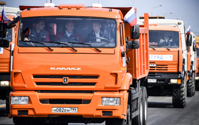 Vlagyimir Putyin mosolyog a Krím-félsziget vezető 19 km-es híd 2018-as átadásán a Daimler résztulajdonában álló Kamaz teherautó volánja mögött. Fotó Nemenov Pool / AFP