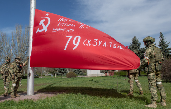 Orosz katonák szovjet győzelmi zászlót húznak fel Herszonban április 19-én – Fotó Sputnik / AFP