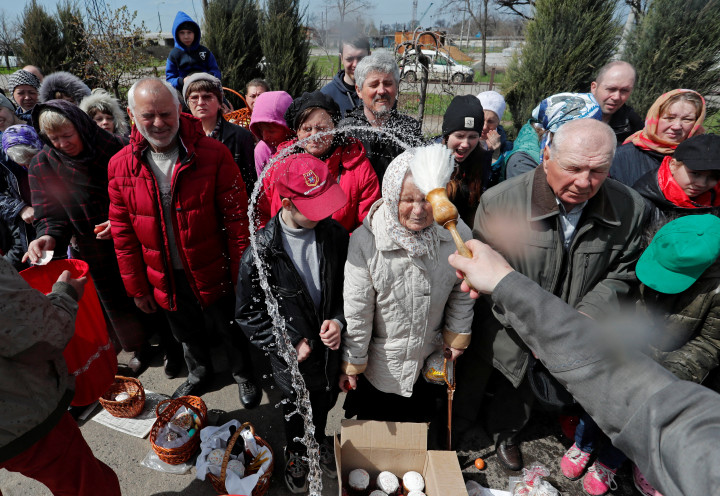 Ételt és embereket szentel egy pap szenteltvízzel Mariupolban – Fotó: Alexander Ermochenko / Reuters