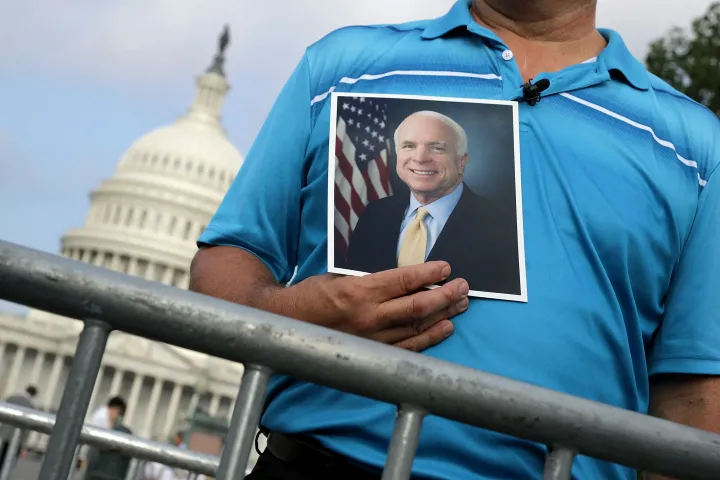 Egy férfi a 81 évesen meghalt szenátor fotóját tartva vár John McCain búcsúztatójára 2018. augusztus 31-én – Fotó: Chip Somodevilla / Getty Images North America / Getty Images via AFP