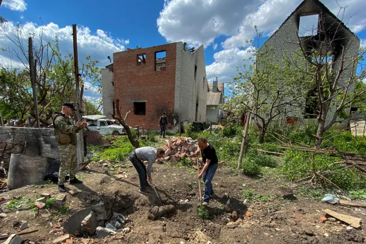 Önkéntesek exhumálják egy tömegsírban talált orosz katona holttestét Mala Rohan faluban, miután az ukrán fegyveres erők visszafoglalták azt Ukrajna Harkiv régiójában 2022. május 19-én – Fotó: Vitalii Hnidyi / Reuters